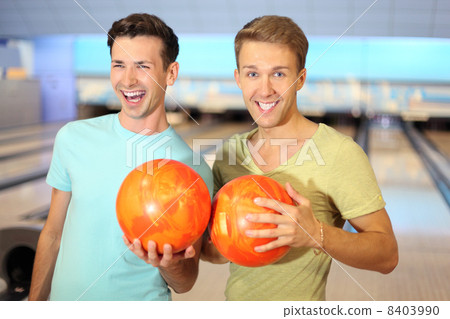 Two happy men make row from orange balls in bowling club; shallo Two happy men make row from orange balls in bowling club; shallo 8403990