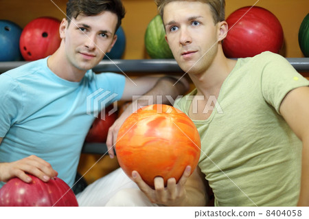 Two beautiful men sit near shelves with balls and hold balls in 8404058