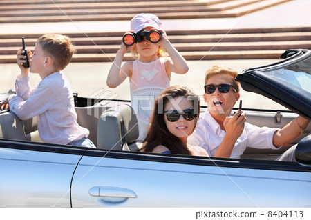 Happy father, mother and two children ride in convertible car an 8404113
