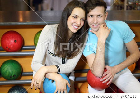 Man and woman sit near shelves with balls and hold balls in bowl Man and woman sit near shelves with balls and hold balls in bowl 8404115