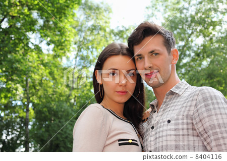 Beautiful man and woman stand in park; green trees and sunny day Beautiful man and woman stand in park; green trees and sunny day 8404116