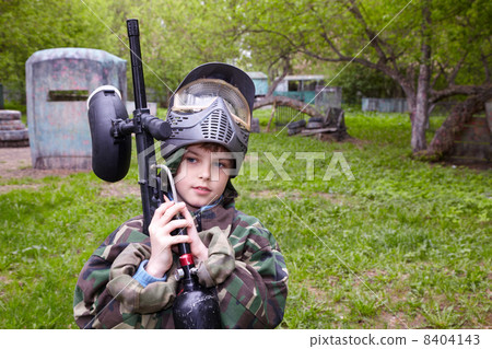 Boy in camouflage with marker for paintball stands at the paintb Boy in camouflage with marker for paintball stands at the paintb 8404143