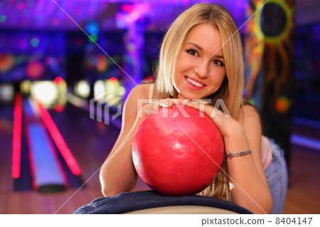 happy beautiful girl stands and bases on red ball in bowling clu 8404147