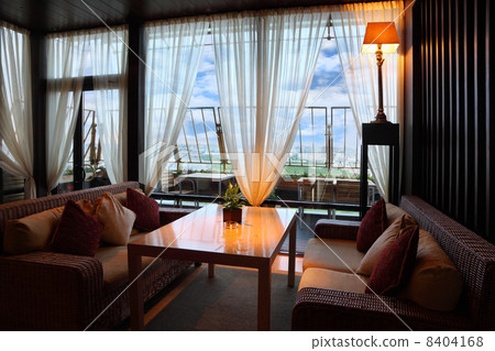 Wicker couches and table in empty comfortable restaurant at even 8404168