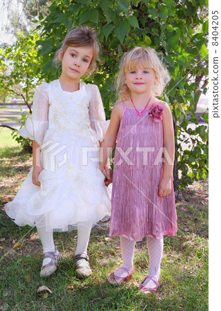 two little girls wearing beautiful dresses holding hands and sta two little girls wearing beautiful dresses holding hands and sta 8404205