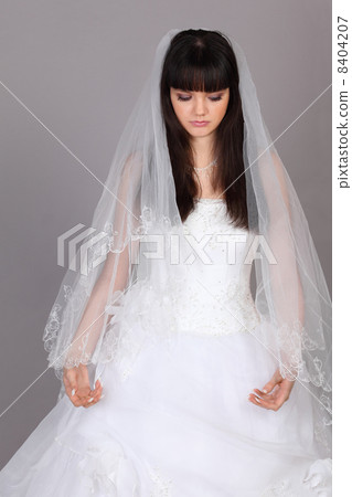 Beautiful melancholy bride dressed in white dress look down on g 8404207