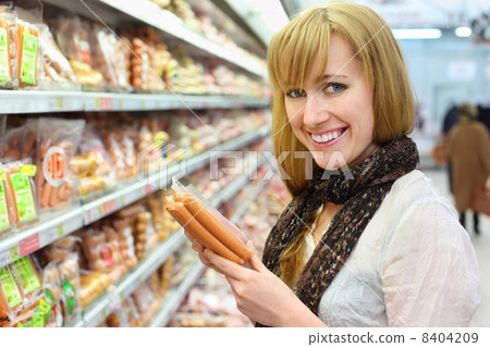 Happy blonde girl wearing white shirt chooses sausage in large s Happy blonde girl wearing white shirt chooses sausage in large s 8404209