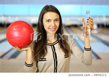 Young brunette woman holds red ball and bottle with water in bow Young brunette woman holds red ball and bottle with water in bow 8404211