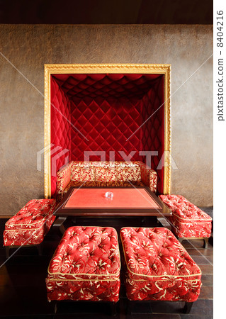 Beautiful red couch in niche, table and stools in empty stylish 8404216