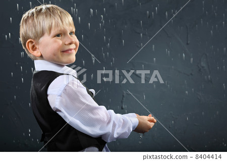 smiling boy dressed in white shirt and black vest stands in rain smiling boy dressed in white shirt and black vest stands in rain 8404414