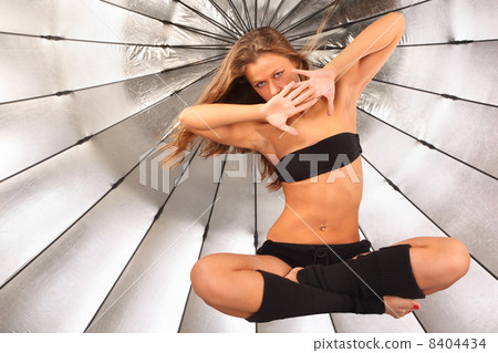 beautiful girl hovers in studio; silver umbrella in background; 8404434