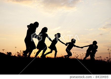 Silhouette, group of happy children playing on meadow, sunset, summertime 8410493