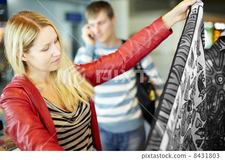 Young woman in red leather jacket considers colorful fabric 8431803