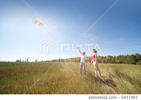 Husband, wife launch kite in field 8431961
