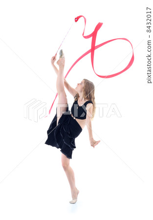 Graceful gymnast in black dress with red ribbon stands on one le 8432017