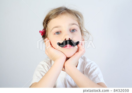 Little melancholy girl in white with glued fake black mustache. 8432030