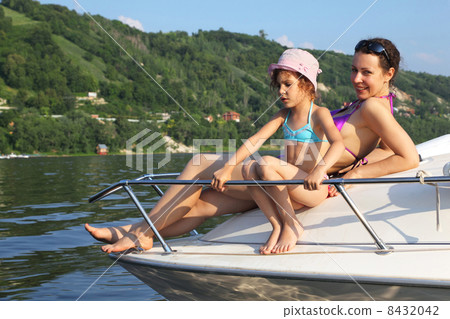 Mother daughter sunbathing on cutter on river, focus on daughter Mother daughter sunbathing on cutter on river, focus on daughter 8432042