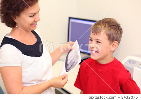 Dentist holds jaw x-ray image for happy boy in dental clinic 8432076