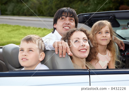 Family of four - parents and son with daughter - sits in a cabr 8432226