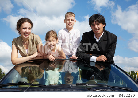 Family of four - parents and two children - stands in cabriolet Family of four - parents and two children - stands in cabriolet 8432280