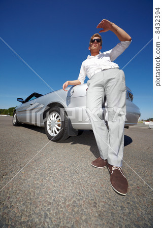 Young man in dark sunglasses stands leaning his elbow on the tru 8432394