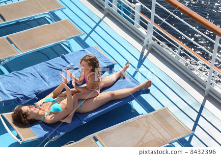 Top view of mother and little daughter lying at deck-chair on sh 8432396