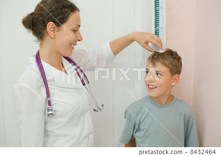 Doctor measures growth smiling boy in medical office, focus on doctor 8432464