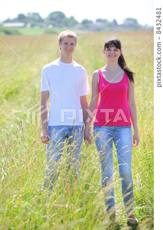 young smile couple hold hands in field near village 8432481