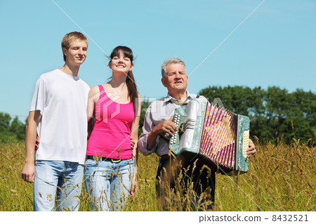 couple stand near grandfather with accordion in field near wood, close eyes 8432521