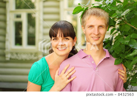 Young couple pose near wooden village house, wife hug husband 8432563