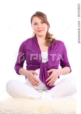Pregnant woman sits on white fur and holds belly isolated on whi Pregnant woman sits on white fur and holds belly isolated on whi 8432603