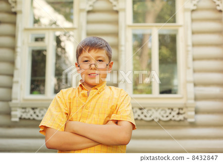 Little boy stand, fold hands near wooden village house 8432847