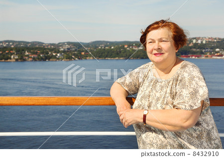 Elderly woman stands at board of ship near railing and looks int Elderly woman stands at board of ship near railing and looks int 8432910