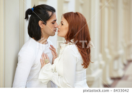Dark-haired man and red-haired woman stand, touching noses and s Dark-haired man and red-haired woman stand, touching noses and s 8433042