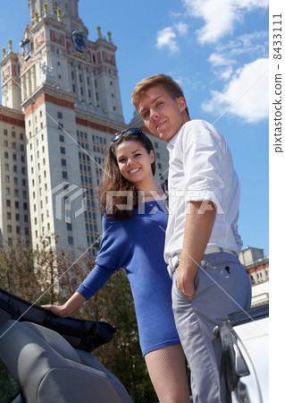 Young smiling couple stands on background of blue sky near to Lo 8433111