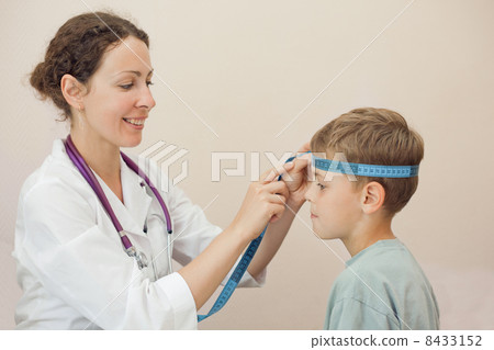 Doctor measures volume of head boy with tape 8433152