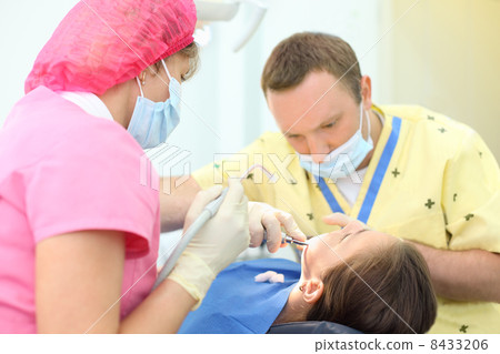 Dentist and assistant treat teeth of girl in dental clinic. Shal Dentist and assistant treat teeth of girl in dental clinic. Shal 8433206