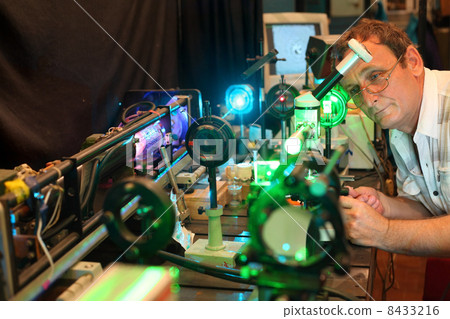 Scientist with glass demonstrate laser of microparticles, scientist in focus Scientist with glass demonstrate laser of microparticles, scientist in focus 8433216
