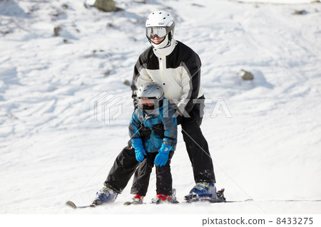 Father supports his child when they slide on alpine skis Father supports his child when they slide on alpine skis 8433275