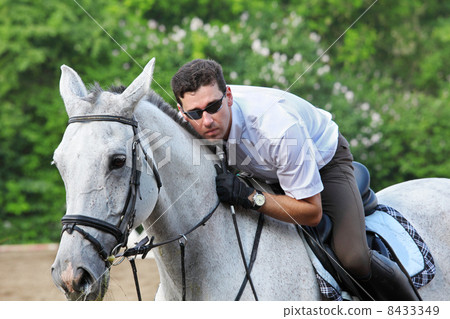 Jockey in glasses with whip hug horse on hippodrome 8433349