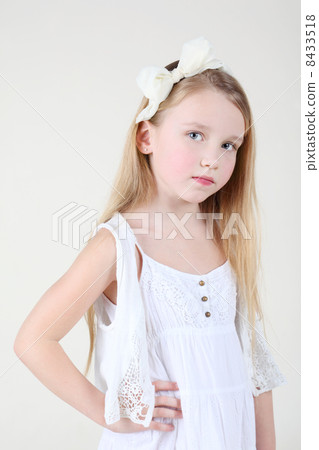 Little sorrowful girl in clean white dress with bow in her hair 8433518