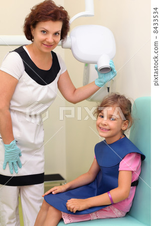 Dentist prepares smiling girl wearing in protective lead apron t 8433534