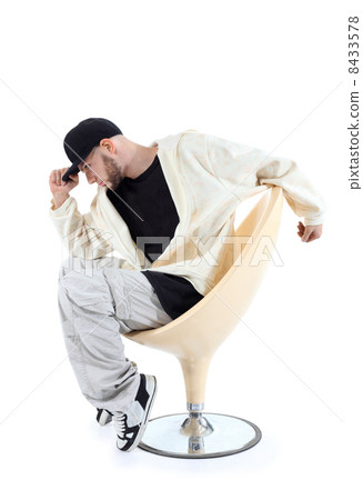 Rapper sits on yellow chair and keeps visor cap isolated on whit 8433578
