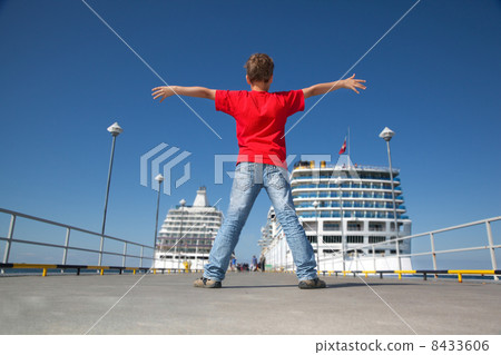 little boy spread hands against background two ships in Tallinn port, back view 8433606