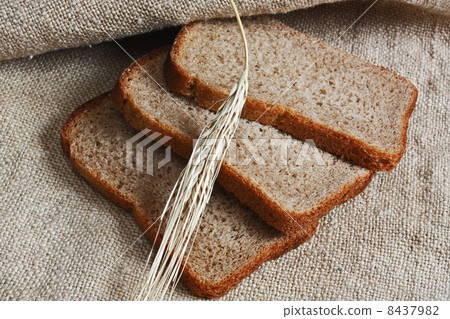 slices of rye bread and ears of corn on a wooden table 8437982