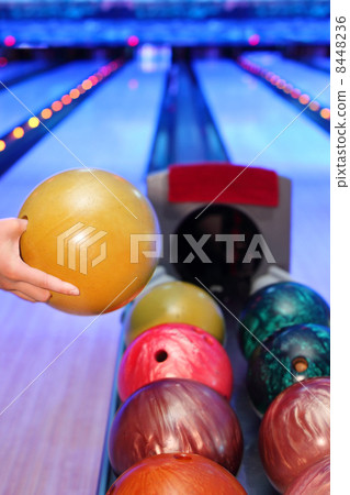 Hand of man, which takes yellow ball for throw in bowling club 8448236