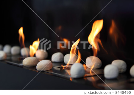 White circular stones and beautiful yellow flames in fireplace White circular stones and beautiful yellow flames in fireplace 8448490