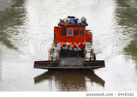 small red boat floats down river and clean river of debris, clea 8448582