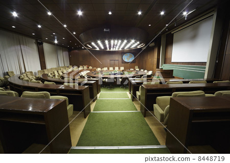 Auditorium with round oak table and beige armchairs around it. 8448719