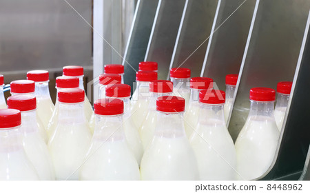 Conveyor with milk bottles at big factory; red covers on bottles Conveyor with milk bottles at big factory; red covers on bottles 8448962